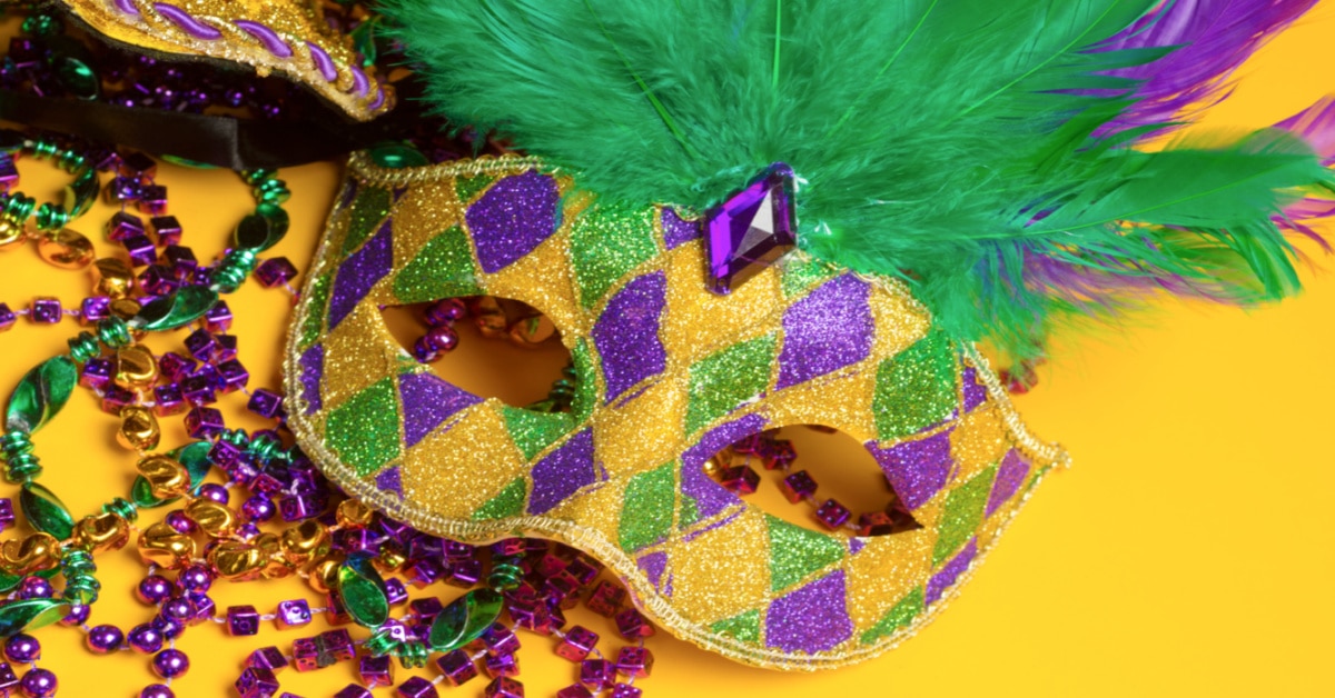 Learning About Mardi Gras colorful yellow purple green Mardi Gras mask and beads on a yellow background
