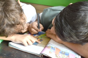 older boy helping kindergartener with a Teaching kindergarten workbook