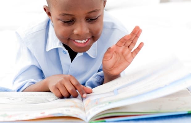 Kindness acts for kids with young black boy reading a kindness book