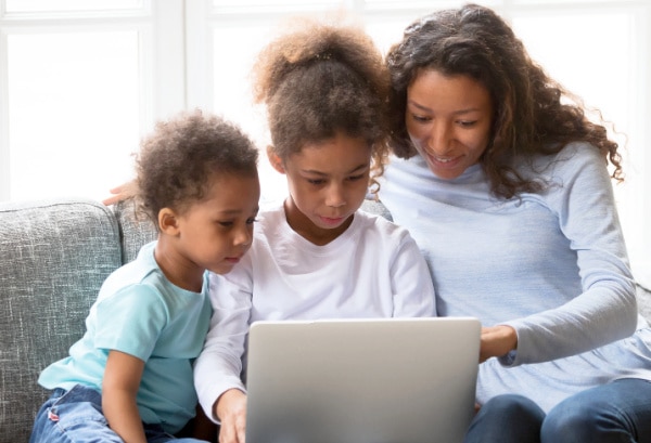 Requirements of Homeschooling home school mom looking at laptop with two kids