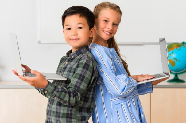 Home school versus virtual school elementary age home learners boy and girl holding laptops