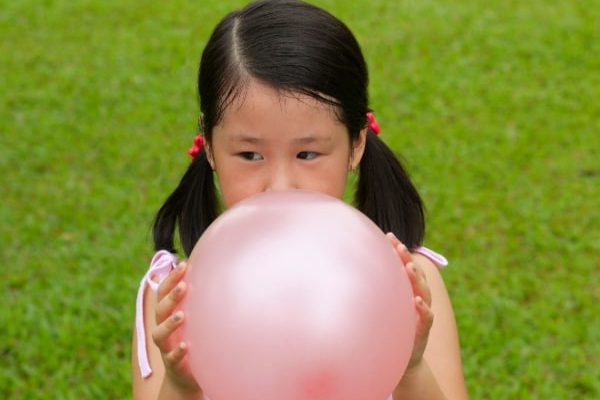 Autism awareness for kids young girls with dark ponytails blowing up a balloons on green grass