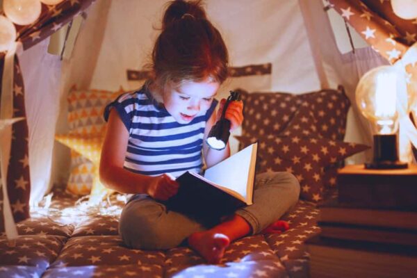 Fun Reading Nook for Kids Ideas And Cheap Reader Corner Tips - girl in a reading corner tent reading with a flashlight