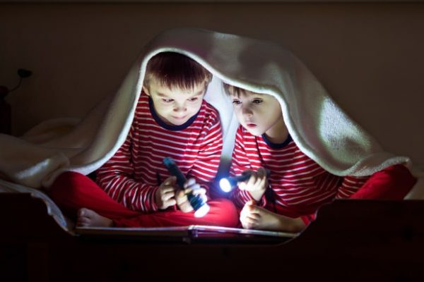 Power Outage Fun With Kids (What can I do at home without electricity?) two kids under a blanket in the dark reading a book with flashlights