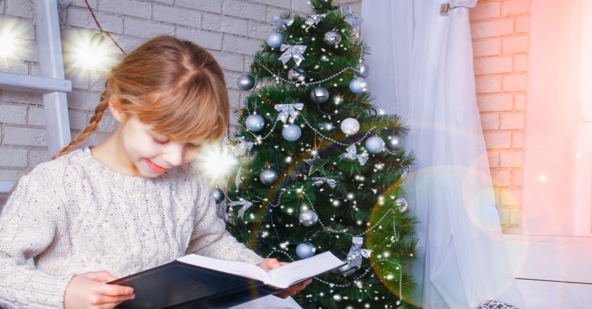 Christmas Present Ideas For Readers little girl smiling while reading in front of Christmas tree