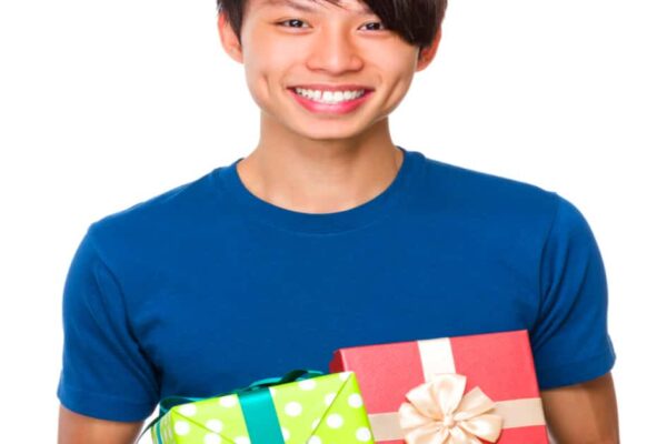 Holiday gifts for college kids: asian college male smiling and holding wrapped christmas gifts