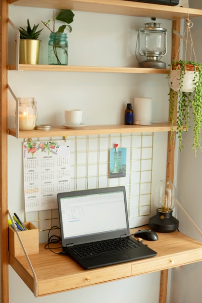 Small Homeschool Room Ideas Drop Down Study Desk with laptop on it and wood shelves above it for homeschool supply storage