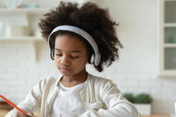 kids podcasts for Black History Month with young Black girl with headphones doing history lessons