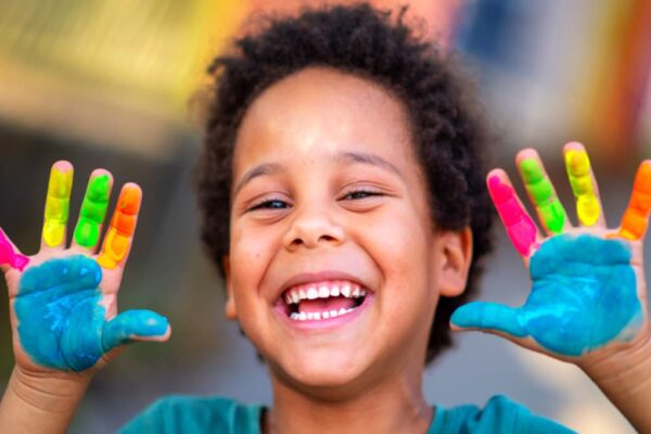 preschool homeschool school supplies smiling African American preschooler boy with hands painted with finger paint
