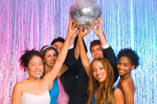All About Homeschool Prom - diverse group of homeschool students at prom holding up a silver disco ball and laughing