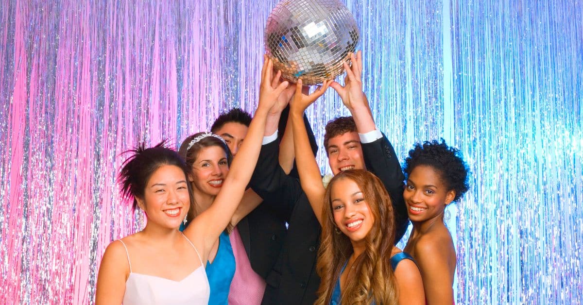 All About Homeschool Prom - diverse group of homeschool students at prom holding up a silver disco ball and laughing