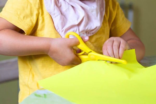 Fun Preschool Scissor Skills Activities Ideas preschooler cutting yellow paper with round safety scissors for kids