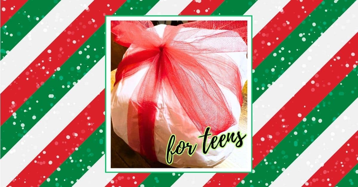 DIY Unwrap Plastic Ball Game For Teens (Saran Wrap Ball Game Rules) - plastic wrap ball in white tissue paper with red bow on a festive green, red and white background
