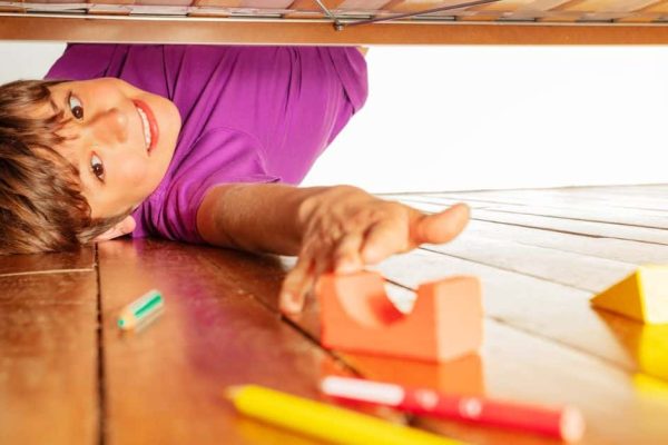 Fun Cleaning Games For Kids - boy smiling and reaching for blocks toys to put away during cleanup games kids activities