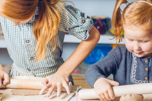 Strewing Sneaky Learning Tip for Savvy Parents - 2 girls rolling out clay on a table to strew