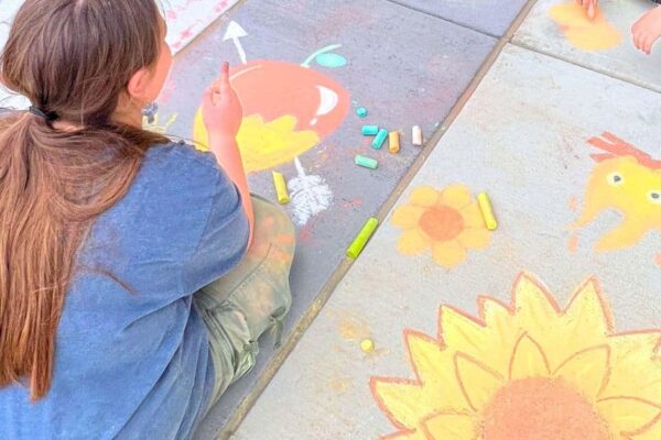 Advice For Homeschool Parents Learn From My Homeschool Scheduling Mistakes - back of a teen working on a community chalk event outdoors